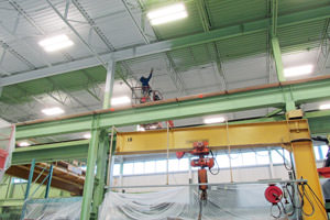 worker spray painting beams in a Grand Rapids manufacturing facility