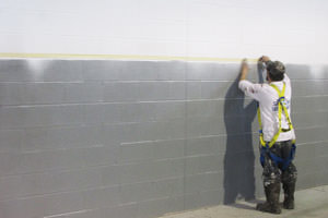 Dearborn, Michigan painter spray painting an industrial building wall