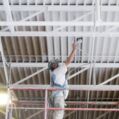 industrial painting contractor spray painting a metal ceiling