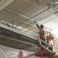 industrial painter spray painting a metal deck ceiling